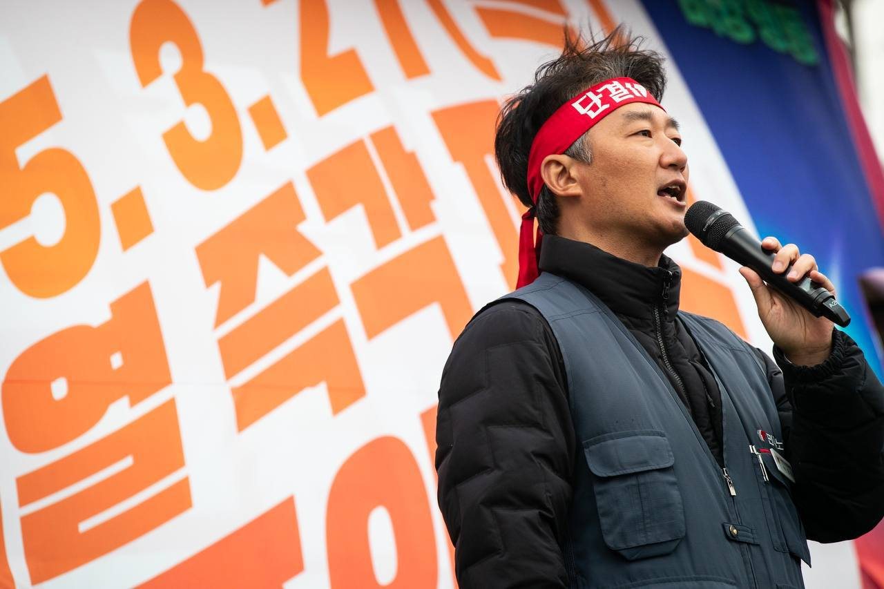 단결투쟁 머리띠를 매고 마이크를 잡은 모습