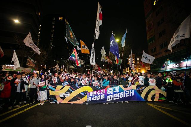 "내란수괴 즉각 윤석열을 파면하라!" 현수막을 든 행진 대열