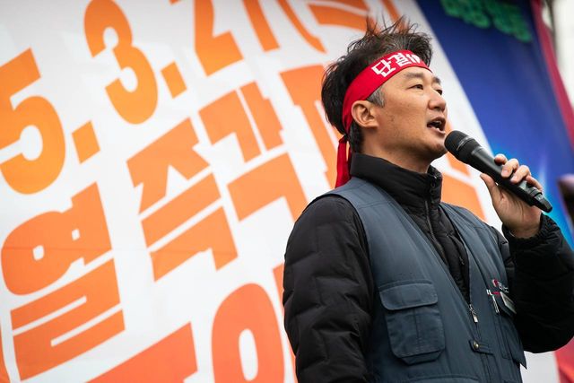 단결투쟁 머리띠를 매고 마이크를 잡은 모습