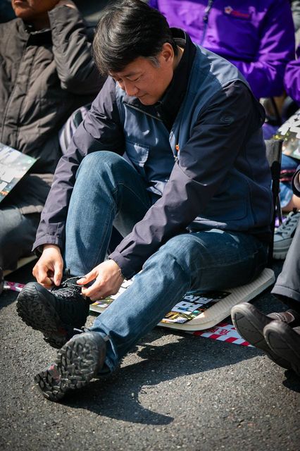 길바닥에 앉아 신발 끈을 고쳐 매는 모습