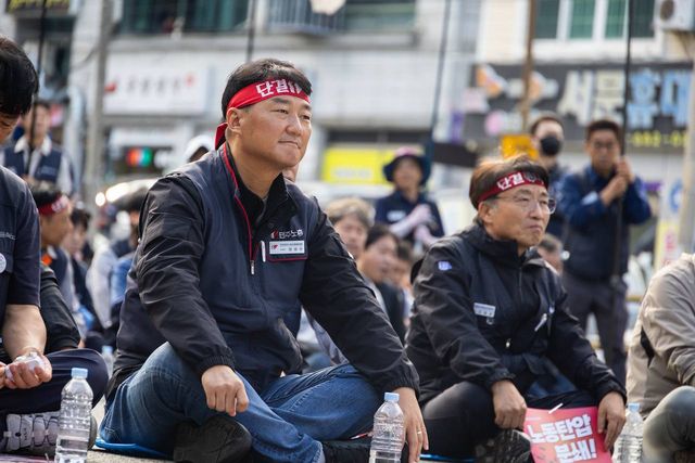 머리띠를 매고 조합원들 사이에 앉은 모습